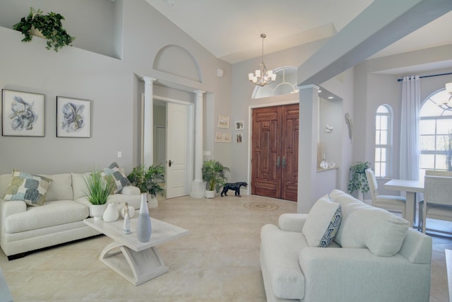 living room featuring ornate columns, a notable chandelier, and high vaulted ceiling