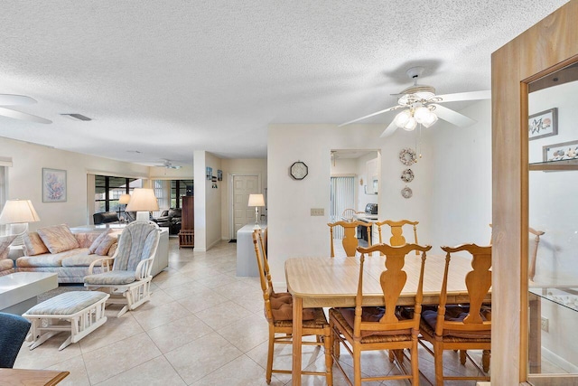 tiled dining room with a textured ceiling and ceiling fan