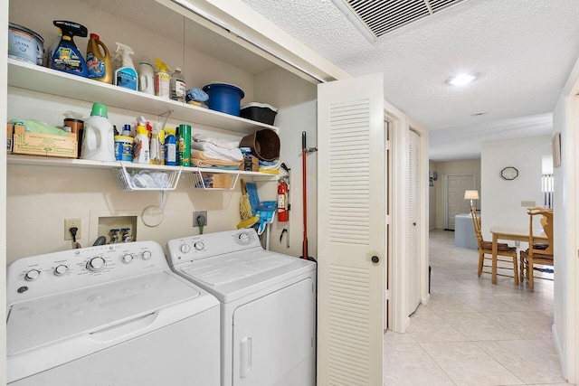 laundry area with separate washer and dryer, light tile patterned floors, and a textured ceiling