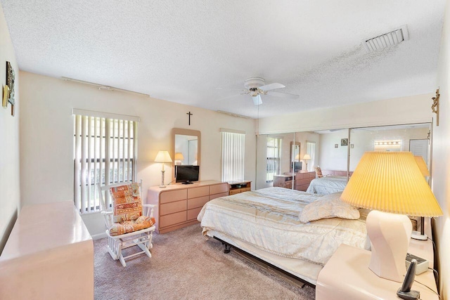 carpeted bedroom with ceiling fan and a textured ceiling