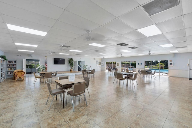 dining area with a drop ceiling, light tile patterned floors, and ceiling fan