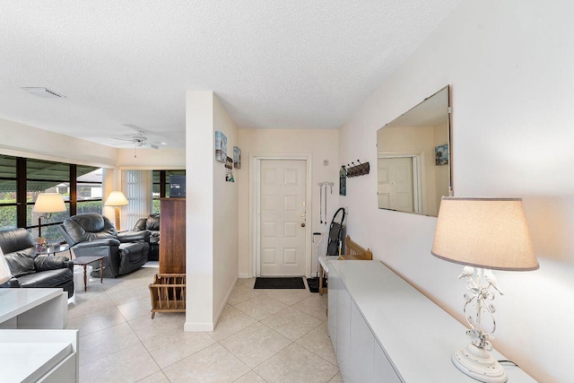 tiled foyer entrance with ceiling fan and a textured ceiling