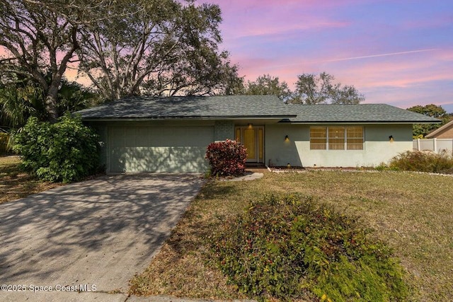 ranch-style home featuring a garage and a yard