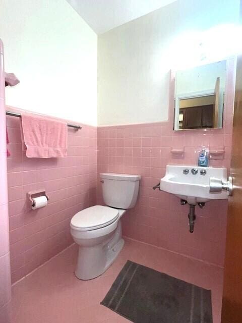 bathroom featuring toilet, tile patterned flooring, sink, and tile walls