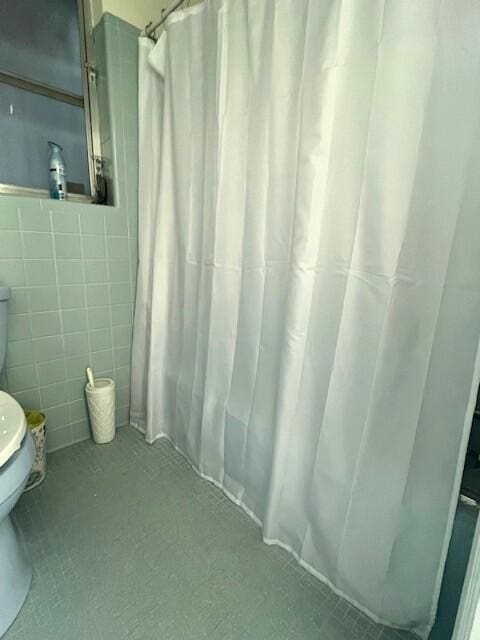 bathroom featuring tile walls and toilet