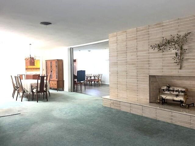 unfurnished living room with a notable chandelier, a tile fireplace, and carpet