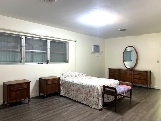 bedroom with dark wood-type flooring and a wall mounted AC