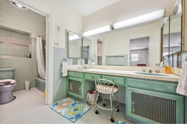 1531 Bacom Point Rd, Pahokee, FL 33476 - bathroom featuring double vanity, tile walls, shower / bath combo with shower curtain, and a wainscoted wall