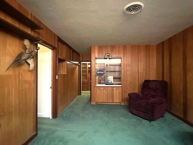 living area featuring dark carpet and wood walls