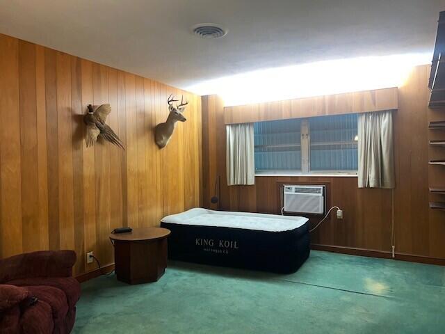 carpeted bedroom featuring a wall unit AC and wood walls