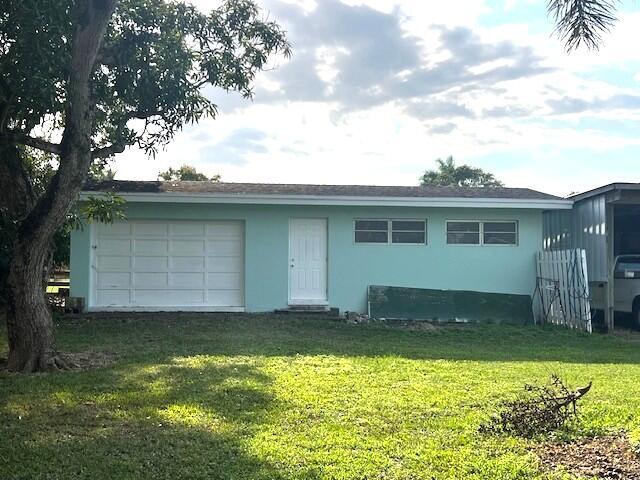 ranch-style home with a garage and a front lawn