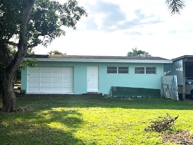 1531 Bacom Point Rd, Pahokee, FL 33476 - view of front of house with stucco siding, a front yard, and a garage