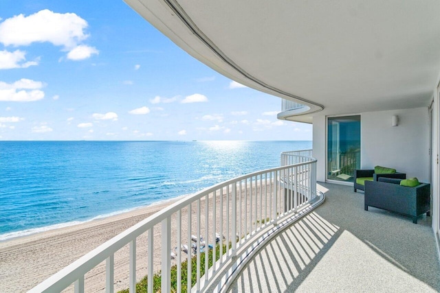 balcony with a water view and a view of the beach