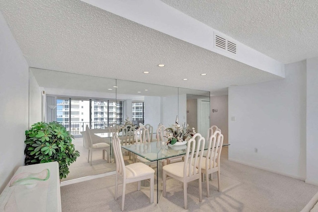 carpeted dining room with a textured ceiling