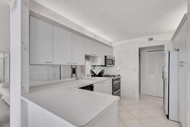 kitchen featuring sink, white cabinetry, stainless steel appliances, a textured ceiling, and kitchen peninsula