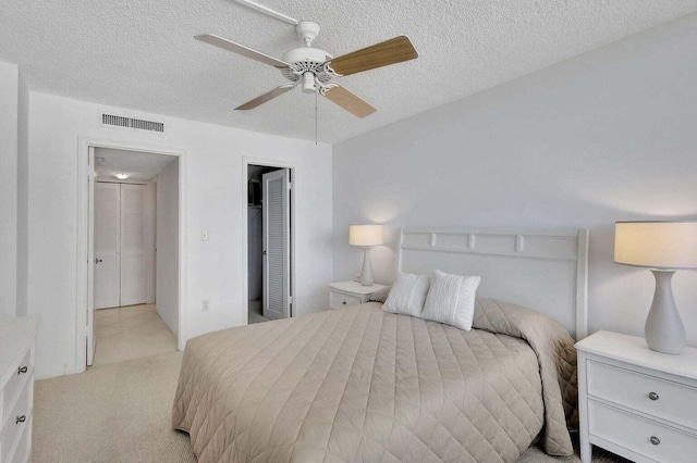 carpeted bedroom with ceiling fan and a textured ceiling