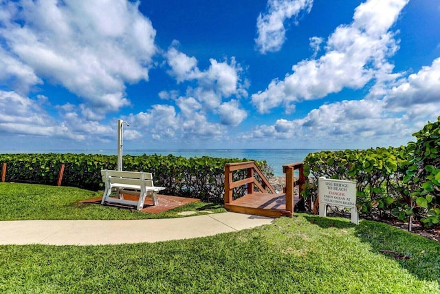 view of home's community with a water view and a lawn