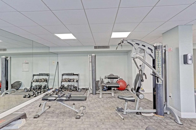 gym with a paneled ceiling and carpet