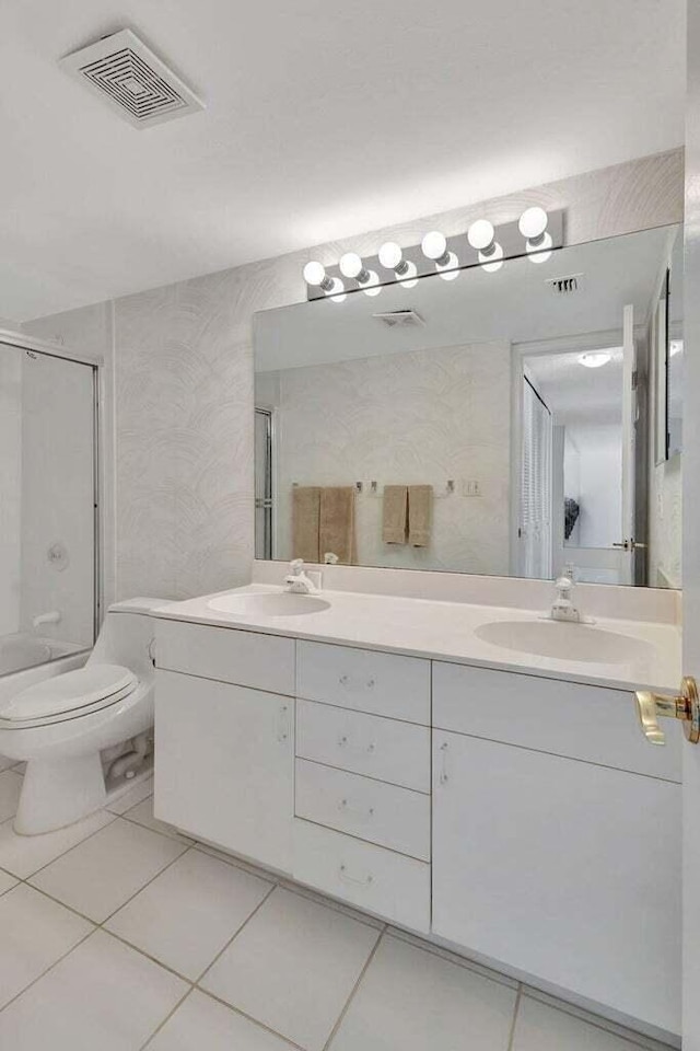 bathroom featuring vanity, toilet, an enclosed shower, and tile patterned flooring