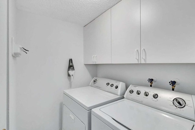 laundry room featuring washer and clothes dryer, cabinets, and a textured ceiling