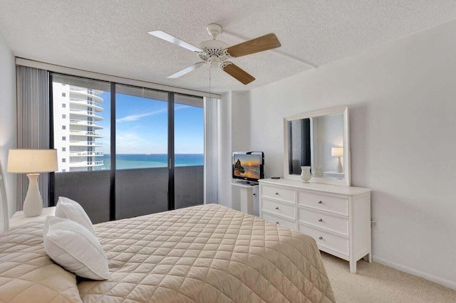 carpeted bedroom featuring ceiling fan, access to exterior, and a textured ceiling