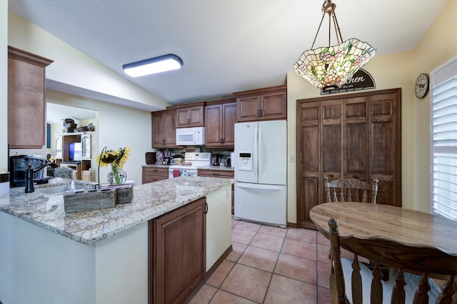 kitchen with vaulted ceiling, light tile patterned flooring, decorative light fixtures, light stone countertops, and white appliances