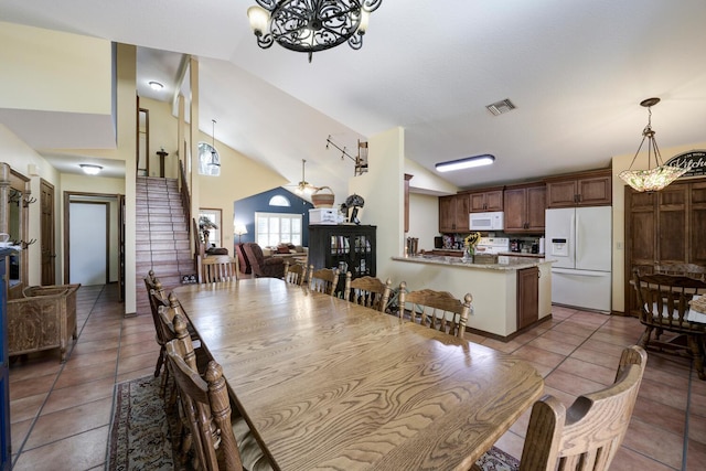 tiled dining room featuring high vaulted ceiling and ceiling fan with notable chandelier