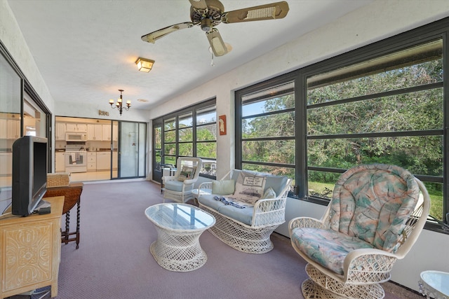 sunroom featuring ceiling fan with notable chandelier