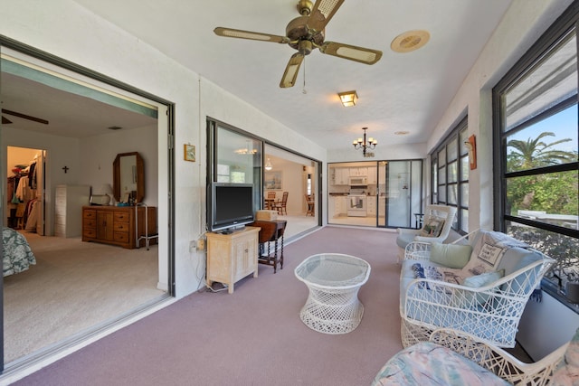 sunroom / solarium featuring ceiling fan with notable chandelier