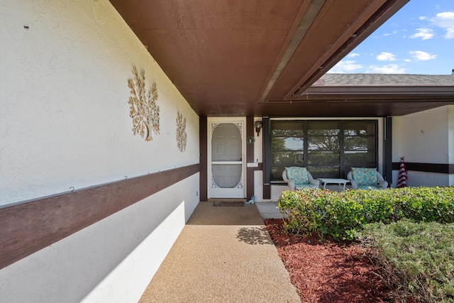 entrance to property featuring stucco siding and a shingled roof