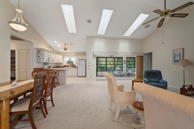 living room with high vaulted ceiling, a skylight, ceiling fan, and light carpet