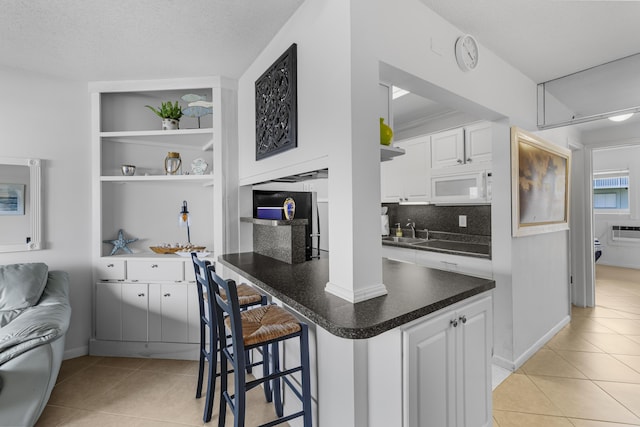 kitchen with white cabinetry, light tile patterned flooring, sink, and a breakfast bar area