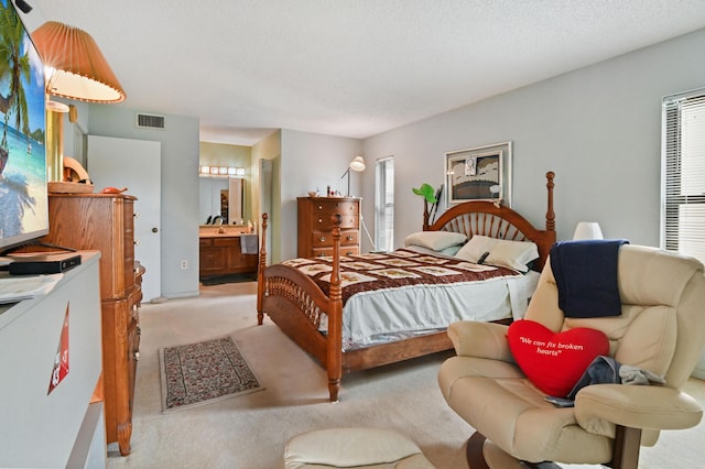 carpeted bedroom with connected bathroom and a textured ceiling