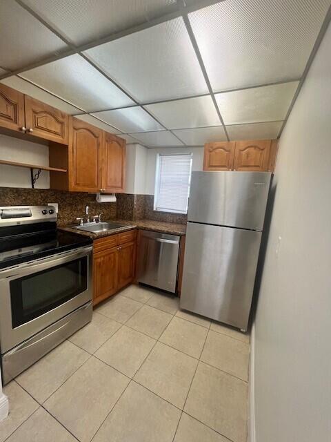 3200 Coral Springs Dr Unit 103, Coral Springs, FL 33065 - kitchen featuring light tile patterned flooring, sink, backsplash, stainless steel appliances, and a drop ceiling