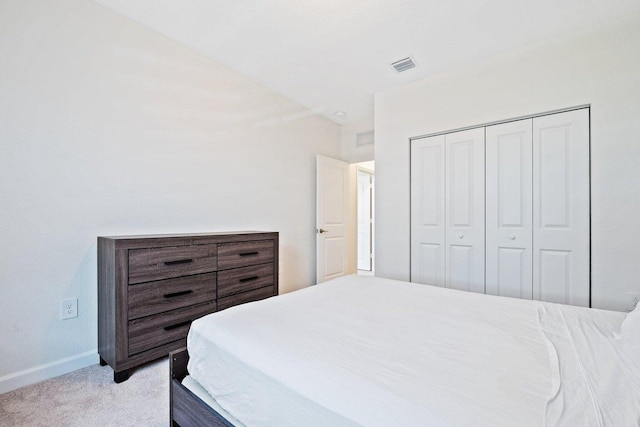 bedroom with lofted ceiling, light colored carpet, and a closet