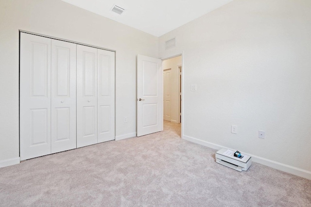 unfurnished bedroom with light colored carpet and a closet