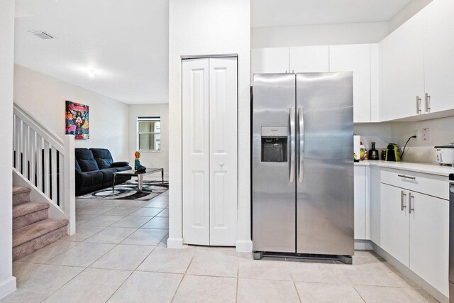 kitchen with appliances with stainless steel finishes, light tile patterned floors, and white cabinets