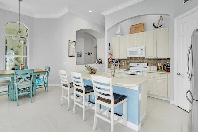 kitchen with white appliances, light countertops, tasteful backsplash, a kitchen bar, and crown molding