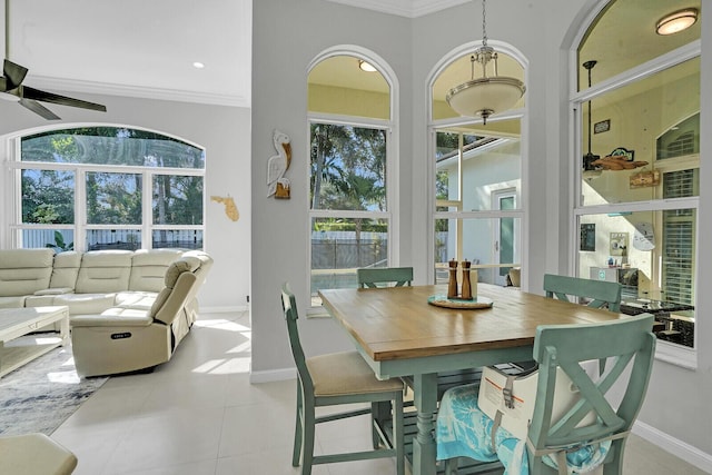 tiled dining area with ceiling fan and ornamental molding