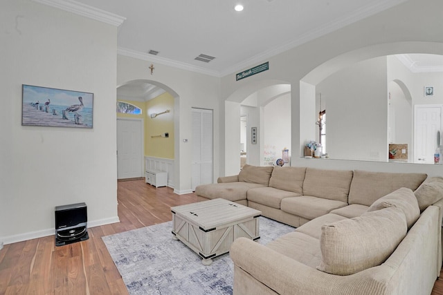 living room with ornamental molding, visible vents, and wood finished floors