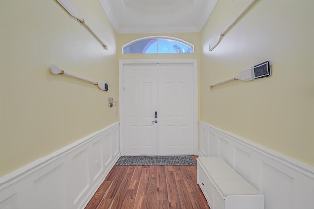 entrance foyer featuring dark wood-type flooring, wainscoting, crown molding, and a decorative wall