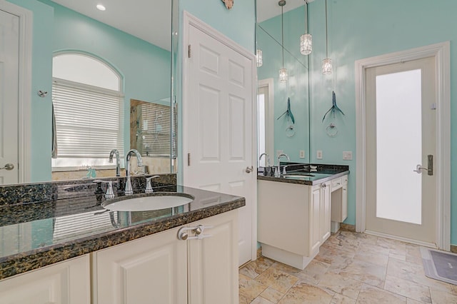 full bath featuring a stall shower, two vanities, and a sink