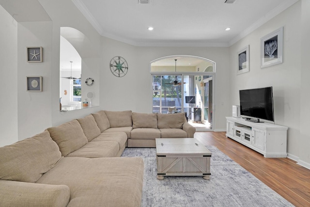 living area with a wealth of natural light, crown molding, baseboards, and wood finished floors