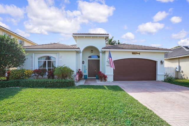 mediterranean / spanish home with a garage, a front yard, decorative driveway, and stucco siding