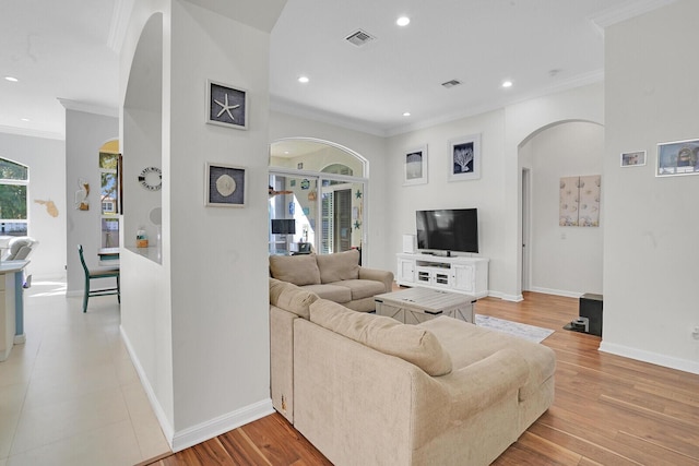 living area featuring visible vents, arched walkways, and crown molding