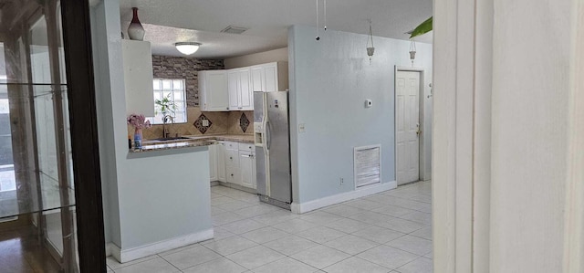 kitchen featuring white cabinetry, sink, light tile patterned floors, and stainless steel fridge