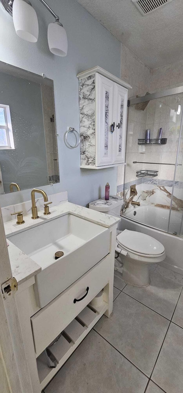 full bathroom with tile patterned flooring, vanity, enclosed tub / shower combo, and toilet