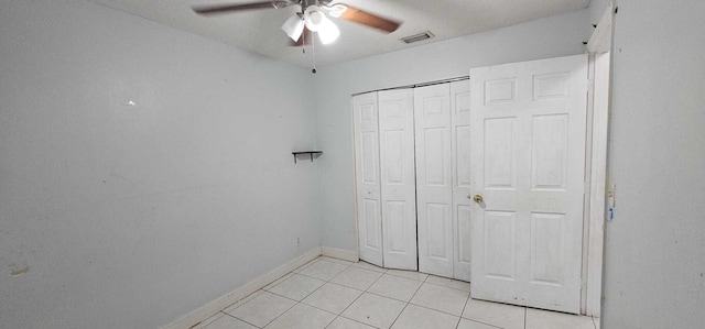 unfurnished bedroom featuring light tile patterned floors, ceiling fan, and a closet