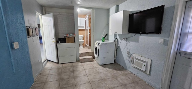 clothes washing area featuring a wall mounted air conditioner, light tile patterned floors, washer and clothes dryer, and a textured ceiling