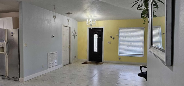 foyer featuring light tile patterned floors, a textured ceiling, and a chandelier